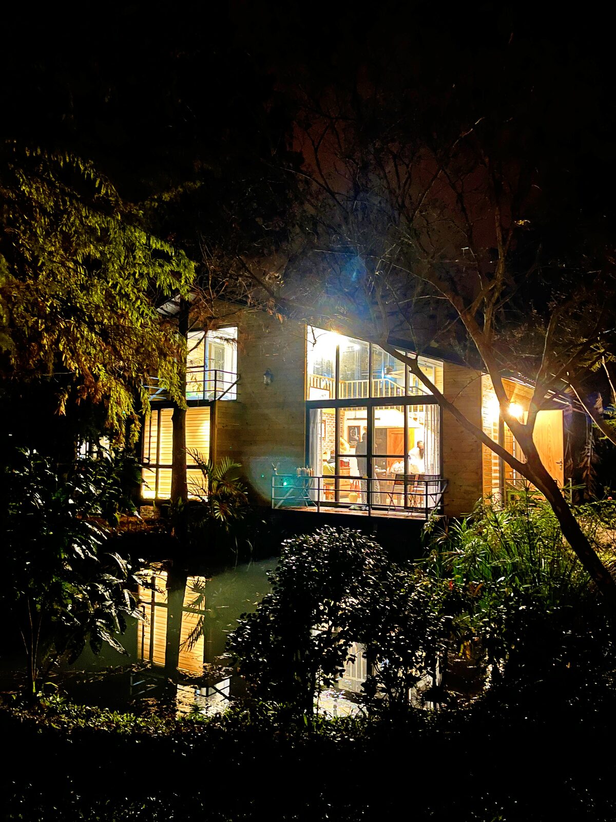 水見曉逐木屋夜景，玻璃窗透出室內燈光並映照在池水上